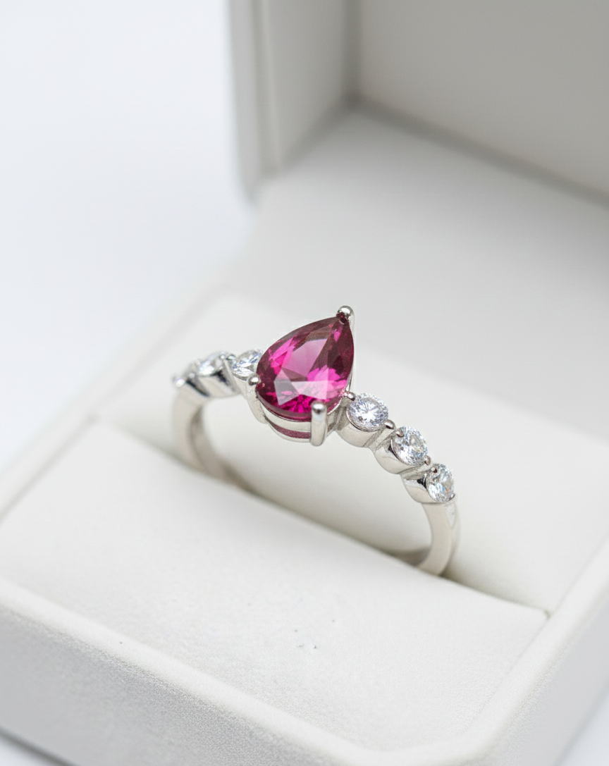 Silver ring with a pink gemstone on a white box