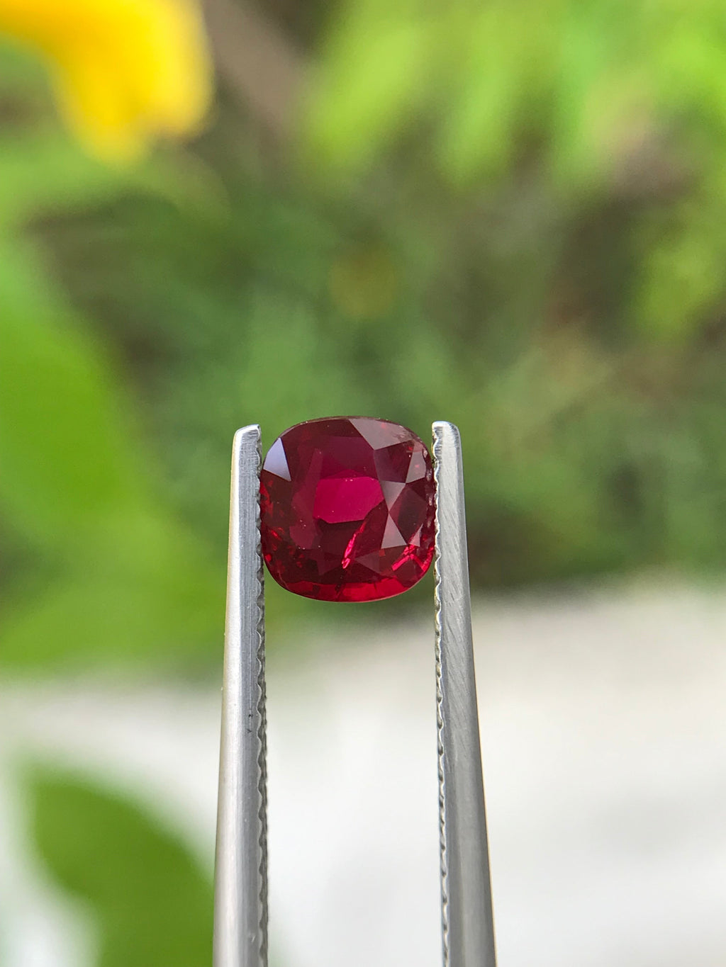 Shiza Gems 1.06 ct cushion cut vivid red unheated natural ruby gemstone held in tweezers.