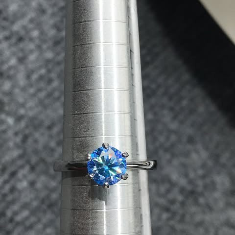 Shiza Gems blue moissanite solitaire ring, round brilliant cut, set in polished sterling silver with a 4-prong setting.