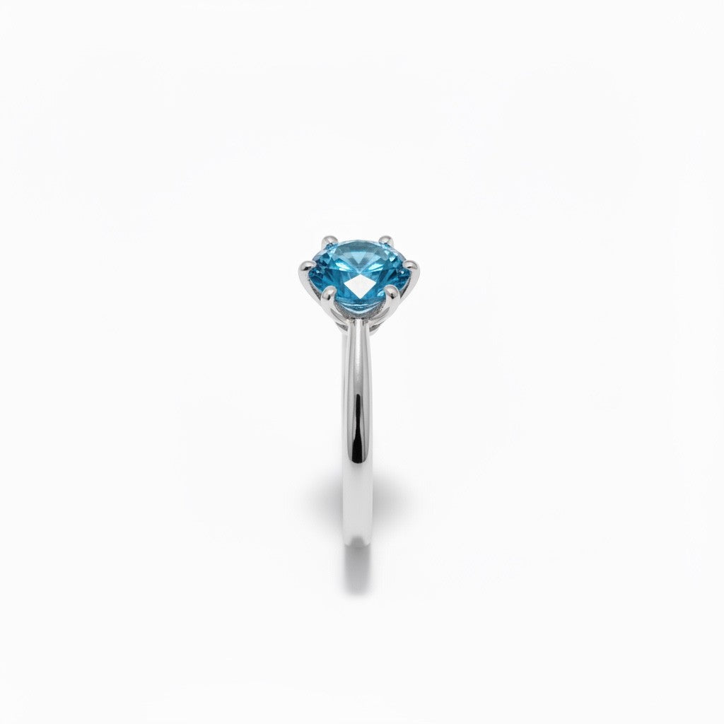 Shiza Gems blue moissanite solitaire ring, round brilliant cut, set in polished sterling silver with a 4-prong setting.