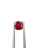 Shiza Gems 1.06 ct cushion cut vivid red unheated natural ruby gemstone held in tweezers against a black background.