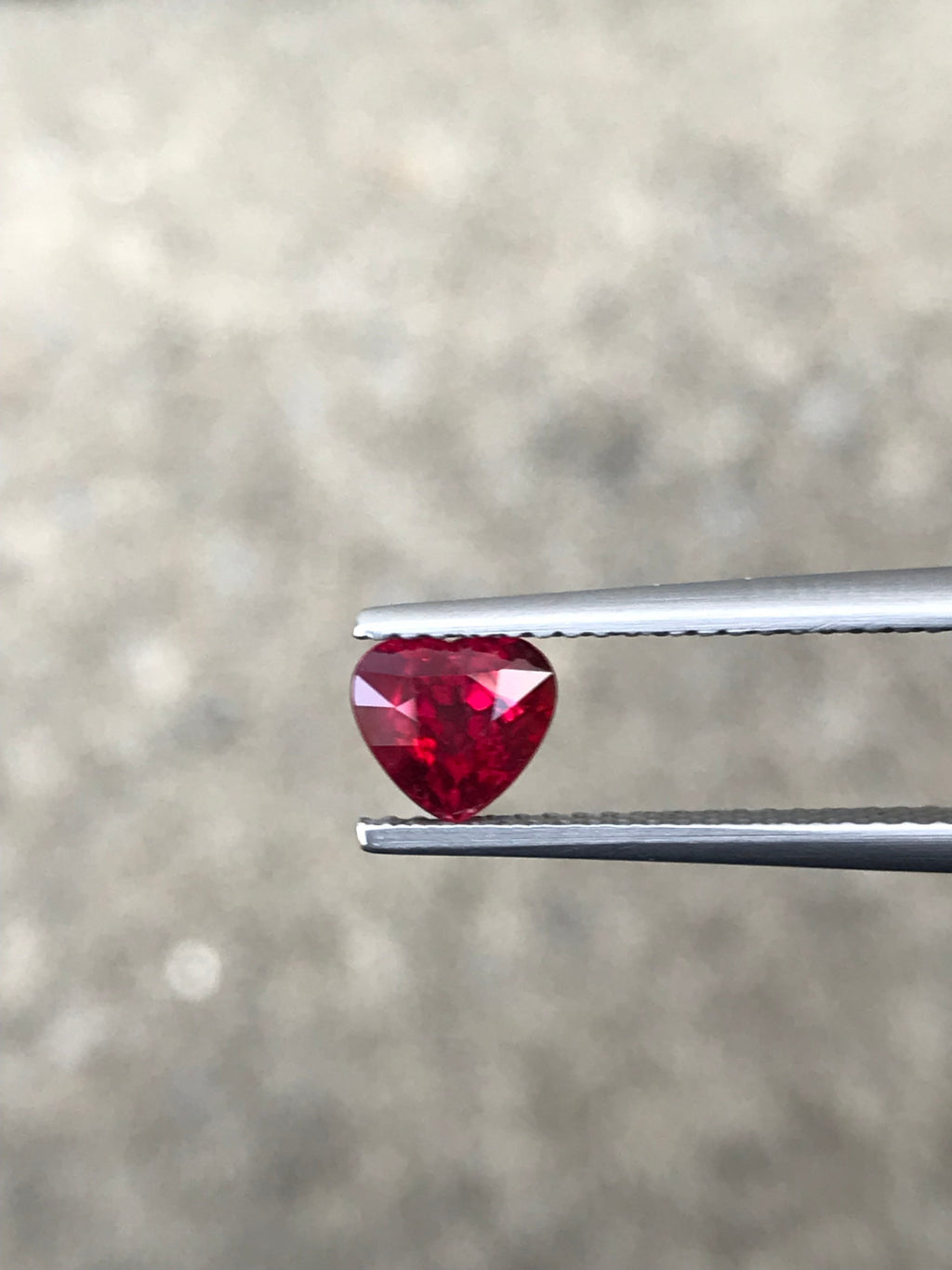 Shiza Gems 1.04 ct vivid red heart-cut unheated ruby from Mozambique, held by tweezers.