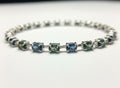 Shiza Gems oval teal sapphires in blue-green shades with cubic zirconia accents on a sterling silver tennis bracelet.