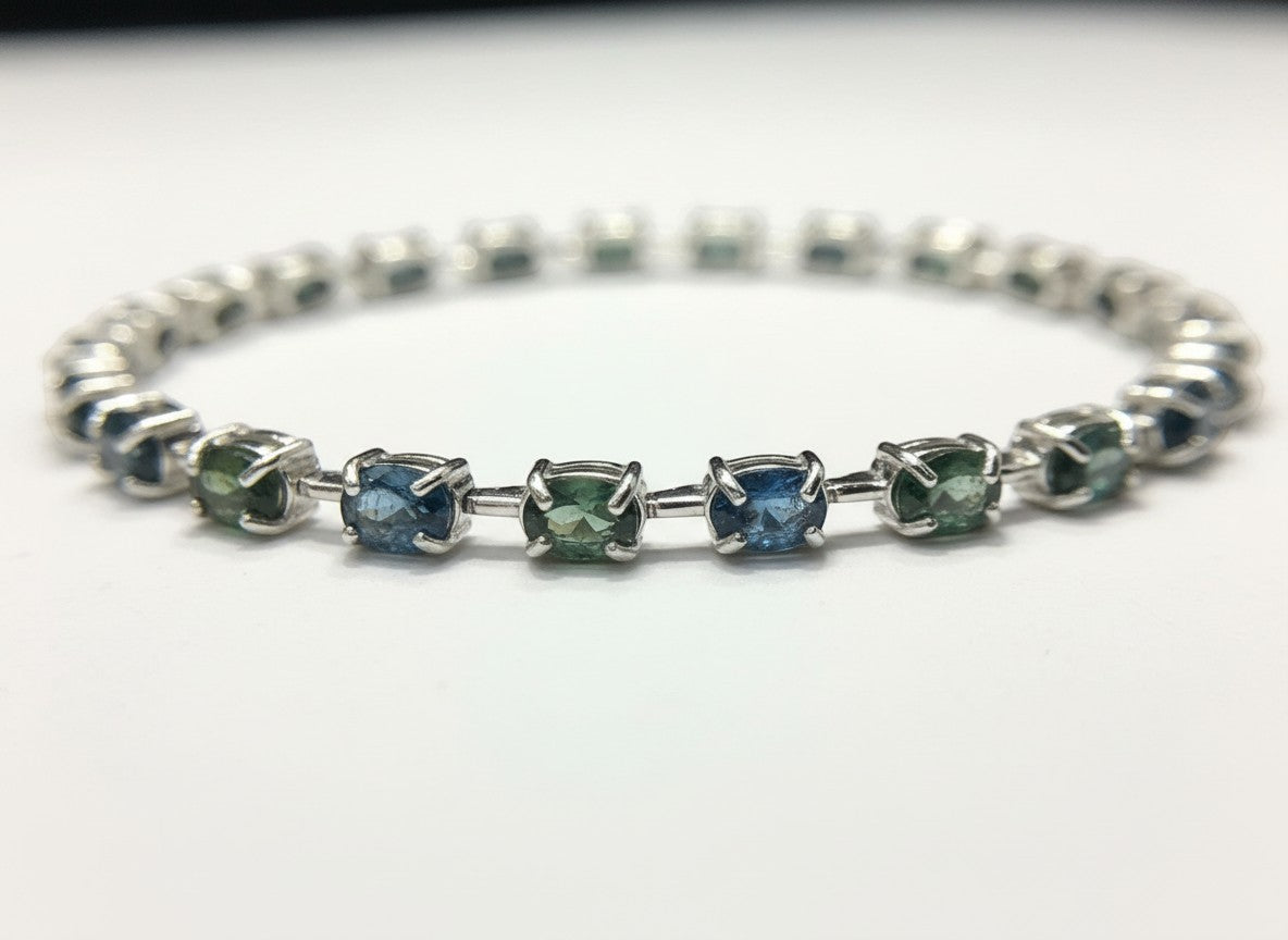 Shiza Gems oval teal sapphires in blue-green shades with cubic zirconia accents on a sterling silver tennis bracelet.
