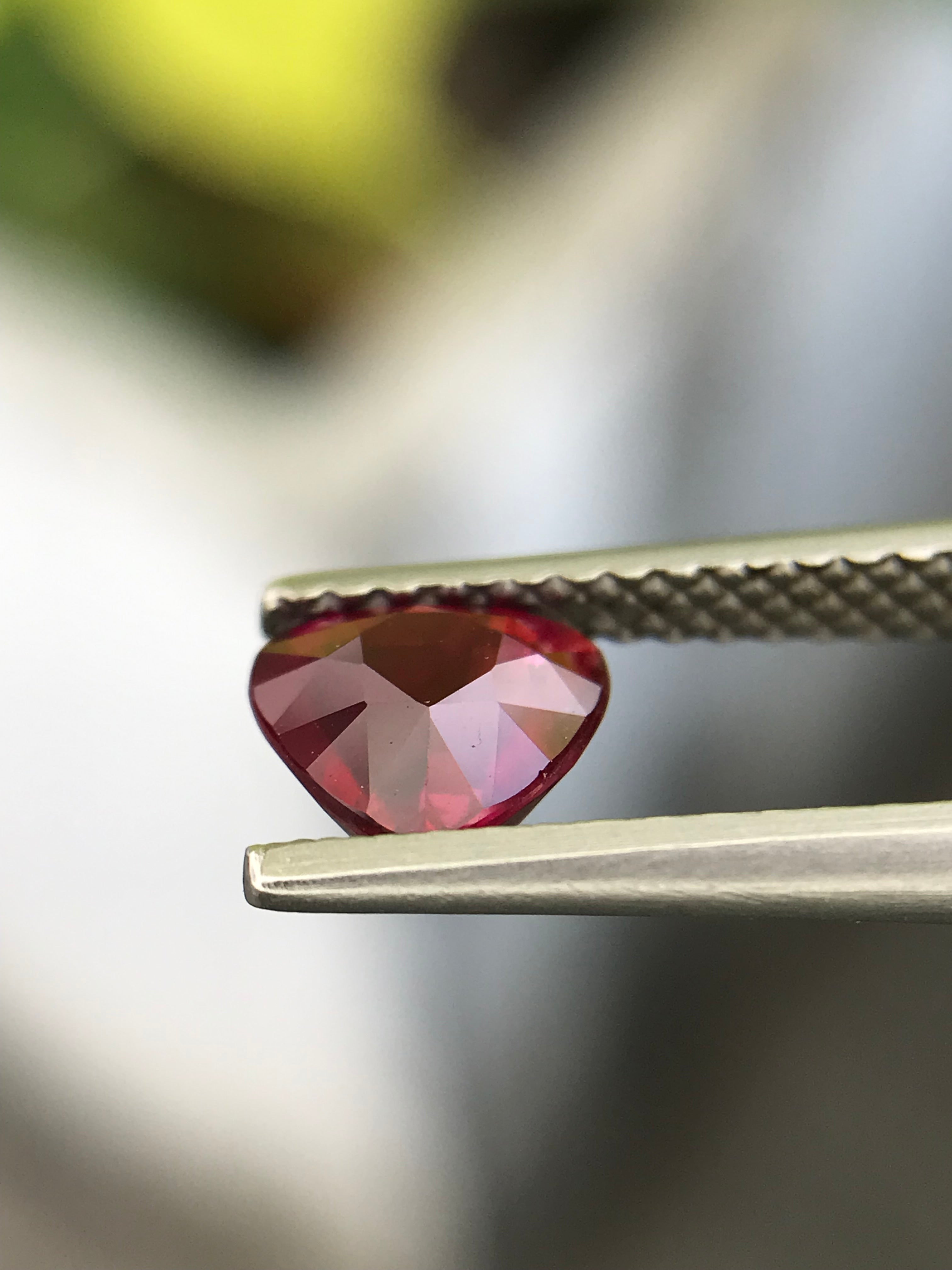 Shiza Gems 1.04 ct unheated heart-cut vivid red ruby from Mozambique, held by tweezers.