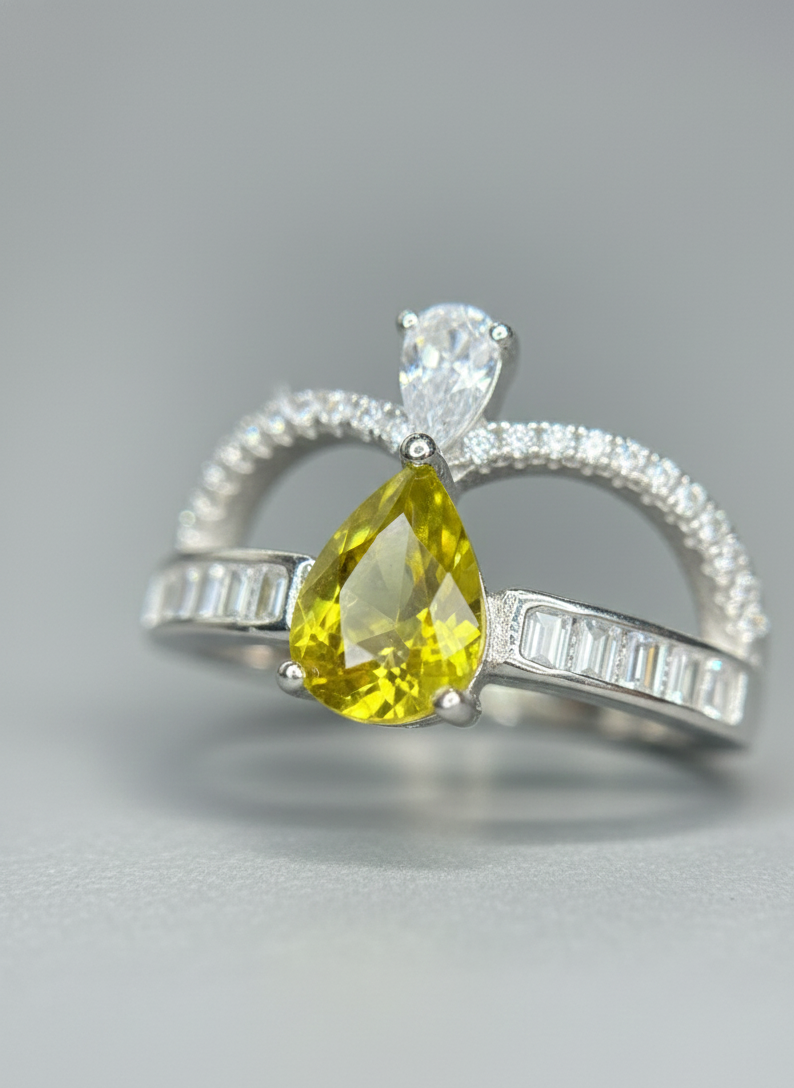 Ring with yellow pear-shaped gemstone and diamond accents on a gray background